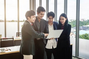 Çeşitli cinsiyetlere sahip Asyalı iş adamları grubu (LGBT), ofisteki toplantı odasındaki dizüstü bilgisayarda başarılı bir iş planı görüyor