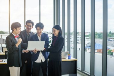 Çeşitli cinsiyetlere sahip Asyalı iş adamları grubu (LGBT), ofisteki toplantı odasındaki dizüstü bilgisayarda başarılı bir iş planı görüyor