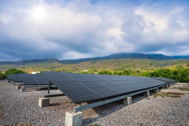 Photovoltaik modüller peyzaj gölündeki yeşil ağaçtaki güneş enerjisi santrali doğa ormanı dağ manzarası baharı beyaz bulut arka planı, alternatif enerji kavramı ve temiz enerji.