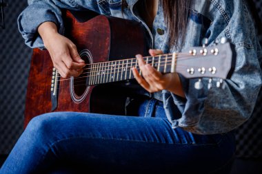 Kadın parmaklarını bir gitarla uzlaştırıp kayıt stüdyosunda şarkı kaydediyor.