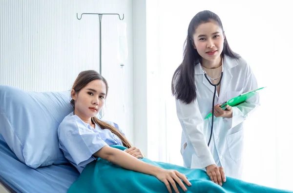 stock image Asian female doctor hold the leg to heal the illness to young female patient on bed with symptom in hospital background,healthcare,medicine concept