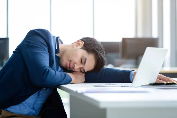 アジアの若いビジネスマンは仕事が遅く ラップトップコンピュータで眠りに落ちたオフィスの部屋の背景に — ストック写真