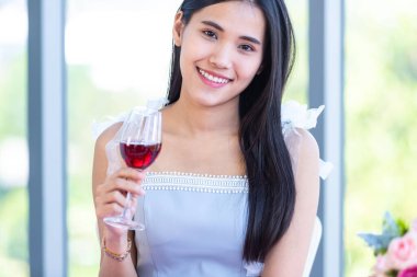 Sevgililer günü konsepti, Asyalı genç bir kız şarap kadehleri ve pembe gül buketi ile masada oturmuş restoranda erkeğini bekliyor.