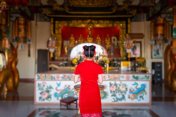 在泰国的中国神龛里 身穿红色传统中式旗袍的美丽可爱的亚洲小女孩向佛像祈祷 以庆祝春节 — 图库照片