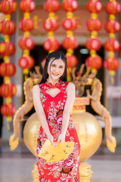 肖像アジアの若い女性はそれに書かれた中国のテキストの祝福と黄色の封筒を保持赤い中国の伝統的な中国のChongsam装飾を身に着けている中国の旧正月の祭りのための幸運 — ストック写真