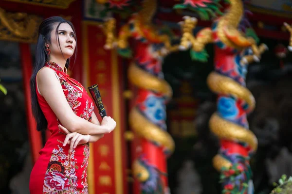 肖像画美しい笑顔アジアの若い女性は タイの中国の神社で中国の旧正月の祭りのための中国のファニングを開催し 赤い伝統的な中国のChongsam装飾を身に着けている — ストック写真