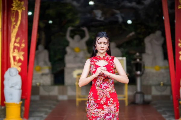 中国の伝統的な赤の装飾を身に着けている美しいアジアの若い女性タイの中国の神社で中国の旧正月祭りの仏像に祈るためのスタンド — ストック写真