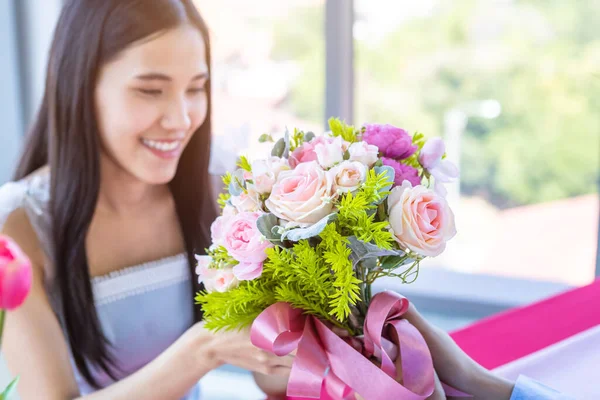 バレンタインデーとアジアの若い幸せなカップルのコンセプト 花束のバラを持つ男笑顔で女性に与える彼女の顔は昼食後に驚きを待っていますレストランの背景で — ストック写真