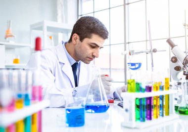İki bilimadamı test tüpünü incelemek için kimya laboratuvarında çalışan bir bilim adamı ya da genç kadın ve erkek araştırmacı laboratuvar analizinde araştırma yapıyor.