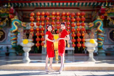 Güzel bir portre gülümsüyor. Küçük şirin bir Asyalı. Çin tapınağında Çin Yeni Yıl Festivali için geleneksel Çin nişanı takan takan iki kız.