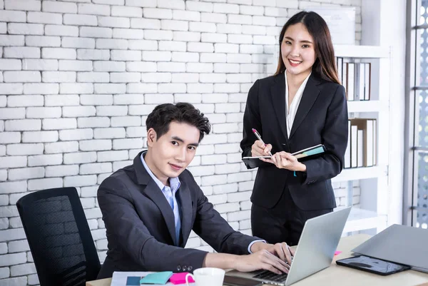 Company executive Young Asian businessman and personal secretary businesswoman partners while working have ideas make a note the successful business plan in a notebook in business profit in office.