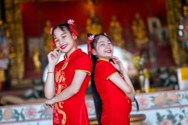 Güzel bir portre gülümsüyor. Küçük şirin bir Asyalı. Çin tapınağında Çin Yeni Yıl Festivali için geleneksel Çin nişanı takan takan iki kız.