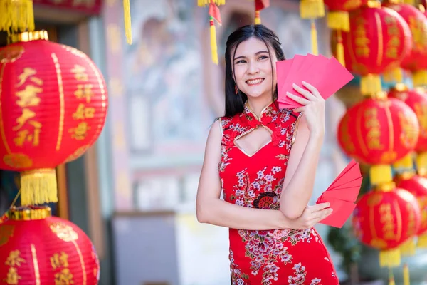 手に赤い封筒を持っている中国の伝統的な中国のChongsam装飾を身に着けているアジアの女性とそれに書かれた中国語のテキストの祝福と提灯は中国の旧正月のための幸運祝福です — ストック写真