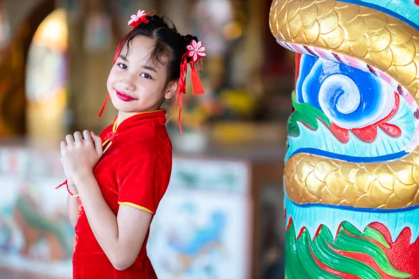 肖像画の美しい笑顔かわいいアジアの女の子は中国の神社で中国の旧正月の祭りのために赤い伝統的な中国のChongsam装飾を着て — ストック写真