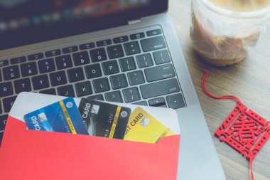 Laptop bilgisayarındaki kırmızı zarfta Çince Blessing yazısıyla Çin Yeni Yıl ikramiyesi olarak ahşap ofis masasında kahve izole edilmiş bir bahar var.