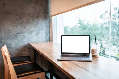 Boş ekranlı dizüstü bilgisayarın bir kopyası. Kahvesini ahşap ofis masasında, arka plandaki gibi beyaz ekran.