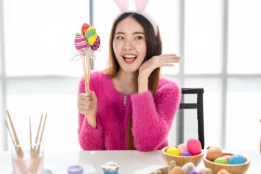 Paskalya bayramı konsepti, mutlu bir gülümseme Asyalı genç bir kadının elinde renkli Paskalya yumurtaları şiş şiş beyaz oda arka planında