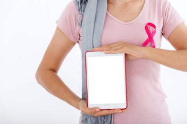 Asyalı bir kadının tablet kullanan portresi. Beyaz göğüs kanseri farkındalığı kurdelesi. Beyaz boş fotokopi stüdyosu arka planı, sağlık sigortası, tıp konsepti.