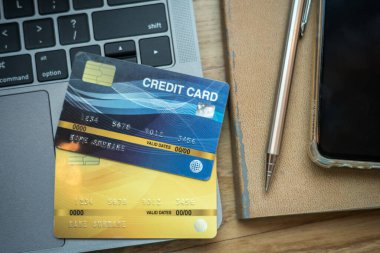 Akıllı telefonlu klavye dizüstü bilgisayarının kredi kartı not defterinde mekanik kalem ve tahta arka planda kahve fincanı, online bankacılık kavramı.