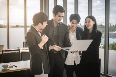 Çeşitli cinsiyetlere sahip Asyalı iş adamları grubu (LGBT), ofisteki toplantı odasındaki dizüstü bilgisayarda başarılı bir iş planı görüyor