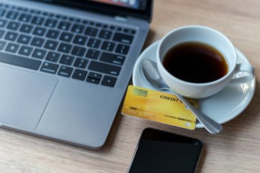 Bilgisayarın kredi kartı, akıllı telefon ve kahve fincanı tahtadan arka planda, çevrimiçi bankacılık kavramı