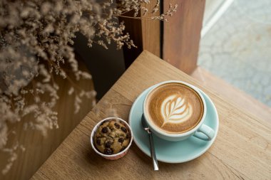 Sütlü sütlü sütlü sütlü sütlü sıcak kahve ve ahşap masanın üstünde ev yapımı muzlu kek. İş konsepti sırasında bir kafede kahvaltı olarak.
