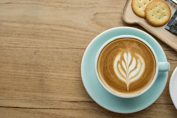 ホットコーヒーラテとラテアートミルク泡のカップマグカップと自家製バナナカップケーキ ビスケットの木の机の上カフェのコーヒーショップで 朝の軽食のコンセプト — ストック写真