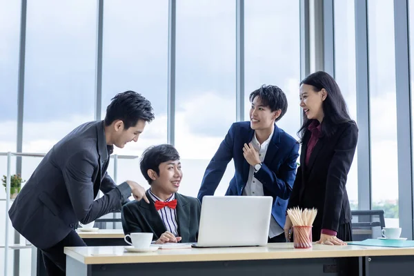 Successful happy workers Group of asian business people with diverse genders (LGBT) Clap hands and congratulate to Homosexual businessman see a successful business plan on the laptop computer in the m