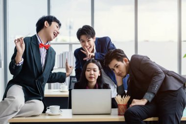 Çeşitli cinsiyetlere (LGBT) sahip Asyalı iş adamlarından oluşan mutlu bir grup işçi şirket desteğiyle ofisteki toplantı odasında şakalaşıyor