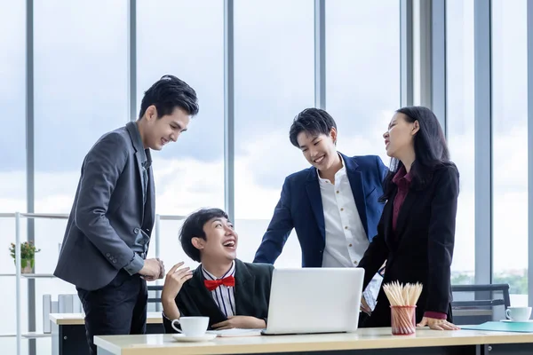 Successful happy workers Group of asian business people with diverse genders (LGBT) and congratulate to Homosexual businessman see a successful business plan on the laptop computer at office