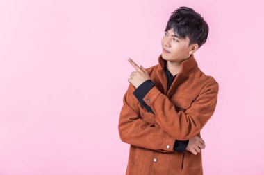 Asyalı genç bir adam iki eli ve parmakları yan gözlerinde pembe boş fotokopi stüdyosunun arka planında izole edilmiş aşka bakan bir kameraya bakıyor..