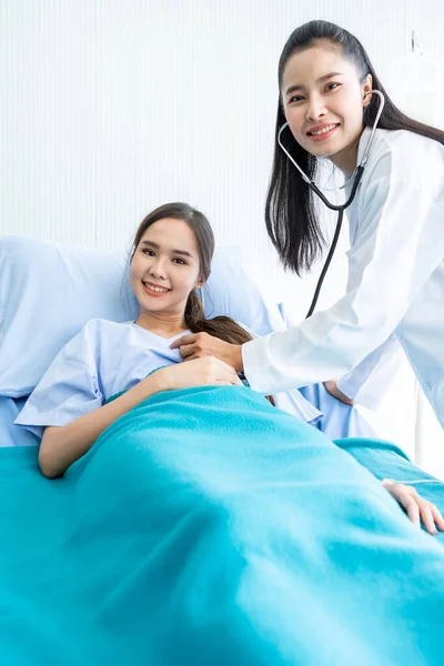 결과를 기록하기 확인하는 의사의 검사를 침대에 아시아인젊은 환자웃는 얼굴은 주변에서 — 스톡 사진