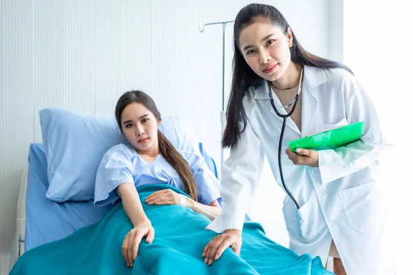 Asian female doctor hold the leg to heal the illness to young female patient on bed with symptom in hospital background,healthcare,medicine concept
