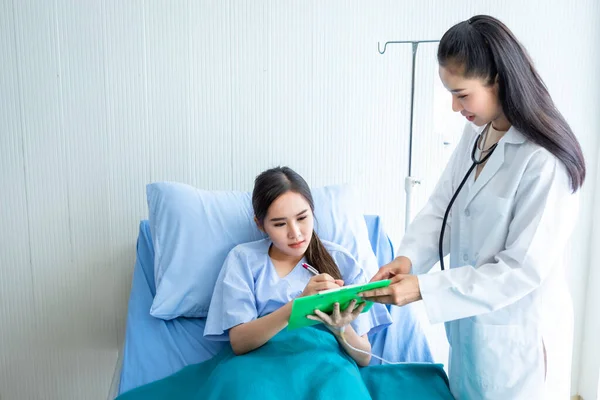 아시아젊은 병실에서 긍정적 감정을 가지고 상담하는 의사와 침대에서 문서에 — 스톡 사진