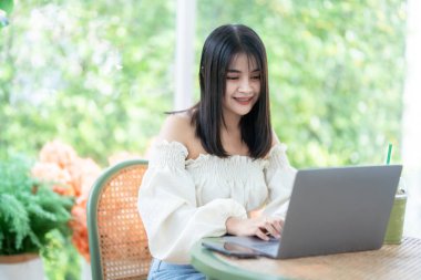 Asyalı serbest çalışan kadın iş kadını konuşuyor. İnternete göz atmak, sohbet etmek, bloglamak, akıllı telefon, kafede not defteri gibi şeyler için dizüstü bilgisayarla günlük işler yapıyor..