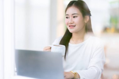 Asyalı serbest çalışanlardan memnun. Günlük iş kadınlarının dizüstü bilgisayarlarla çalışmasından ve kahve ve akıllı telefonları arka plan, iletişim konsepti gibi kafelerde tutmasından memnun.