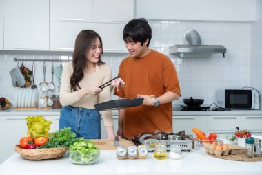 Genç Asyalıyı sevmenin mutlu portresi neşe dolu bir yemek hazırlarken yemek pişirmenin, sebze, et, ekmek pişirmenin ve bir evde ya da mutfakta hayat boyu kalmanın keyfini çıkarmanın.