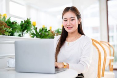 Asyalı serbest çalışan kadın iş kadını konuşuyor. İnternete göz atmak, sohbet etmek, bloglamak, akıllı telefon, kafede not defteri gibi şeyler için dizüstü bilgisayarla günlük işler yapıyor..