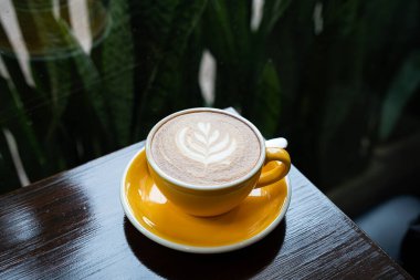 Sütlü sütlü sütlü sütlü sıcak kahve fincanı ahşap masanın üstünde. Kafedeki bir kafede kahvaltı olarak, iş konsepti sırasında, klasik tarzda.