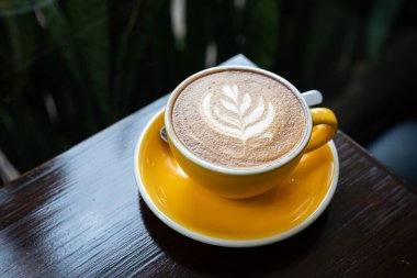 Sütlü sütlü sütlü sütlü sıcak kahve fincanı ahşap masanın üstünde. Kafedeki bir kafede kahvaltı olarak, iş konsepti sırasında, klasik tarzda.