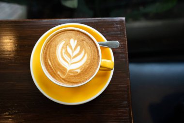 Sütlü sütlü sütlü sütlü sıcak kahve fincanı ahşap masanın üstünde. Kafedeki bir kafede kahvaltı olarak, iş konsepti sırasında, klasik tarzda.