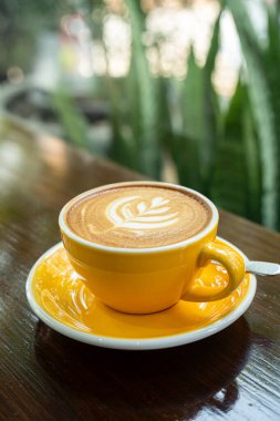 Sütlü sütlü sütlü sütlü sıcak kahve fincanı ahşap masanın üstünde. Kafedeki bir kafede kahvaltı olarak, iş konsepti sırasında, klasik tarzda.