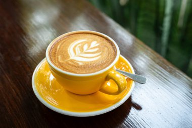 Sütlü sütlü sütlü sütlü sıcak kahve fincanı ahşap masanın üstünde. Kafedeki bir kafede kahvaltı olarak, iş konsepti sırasında, klasik tarzda.