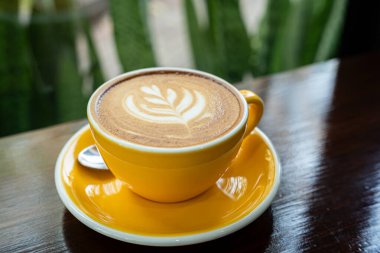 Sütlü sütlü sütlü sütlü sıcak kahve fincanı ahşap masanın üstünde. Kafedeki bir kafede kahvaltı olarak, iş konsepti sırasında, klasik tarzda.