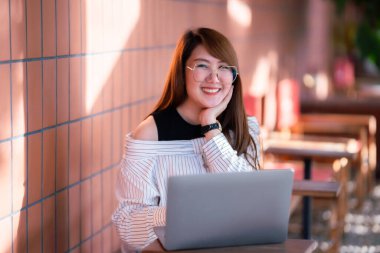 Asyalı serbest çalışan kadın iş kadını konuşuyor. İnternete göz atmak, sohbet etmek, bloglamak, akıllı telefon, kafede not defteri gibi şeyler için dizüstü bilgisayarla günlük işler yapıyor..