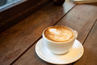 Sütlü sütlü sütlü sütlü sıcak kahve fincanı ahşap masanın üstünde. Kafedeki bir kafede kahvaltı olarak, iş konsepti sırasında, klasik tarzda.