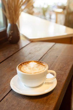 Sütlü sütlü sütlü sütlü sıcak kahve fincanı ahşap masanın üstünde. Kafedeki bir kafede kahvaltı olarak, iş konsepti sırasında, klasik tarzda.