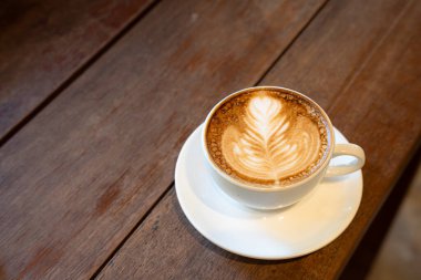 Sütlü sütlü sütlü sütlü sıcak kahve fincanı ahşap masanın üstünde. Kafedeki bir kafede kahvaltı olarak, iş konsepti sırasında, klasik tarzda.