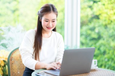 Asyalı serbest çalışan kadın iş kadını konuşuyor. İnternete göz atmak, sohbet etmek, bloglamak, akıllı telefon, kafede not defteri gibi şeyler için dizüstü bilgisayarla günlük işler yapıyor..