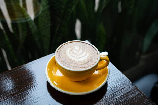 Sütlü sütlü sütlü sütlü sıcak kahve fincanı ahşap masanın üstünde. Kafedeki bir kafede kahvaltı olarak, iş konsepti sırasında, klasik tarzda.